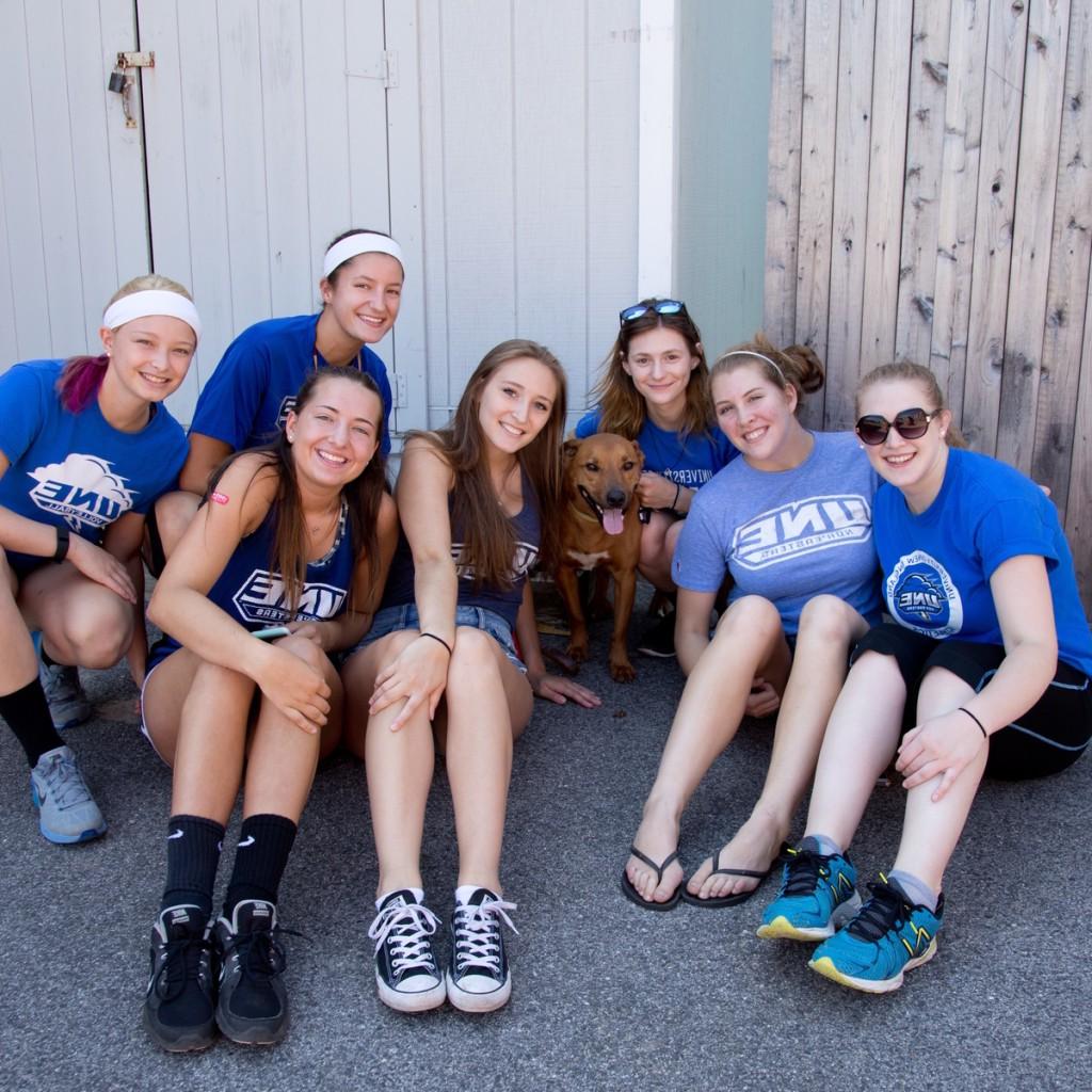 一群学生穿着蓝色t恤和一只狗在外面摆造型