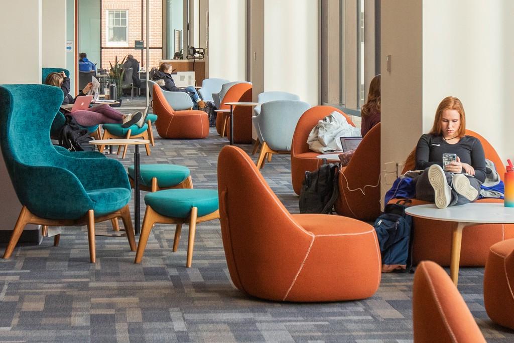  students relax in comfy chairs on the second floor of the Ripich Commons
