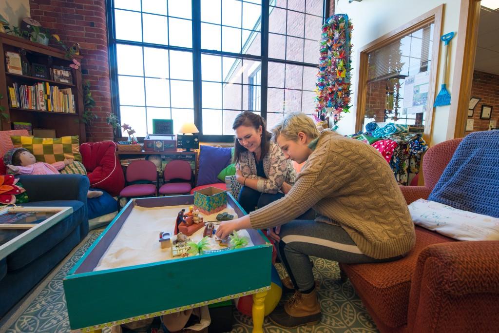 A U N E student works with a student at a sensory table at the Dempsey Center
