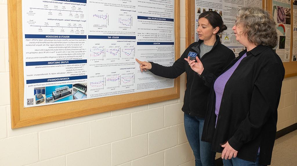 A student presents their research poster to a faculty member