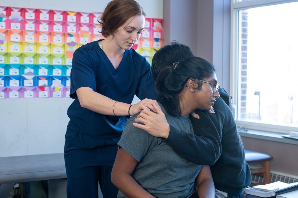 Two C O M students practice osteopathic manipulation on another student