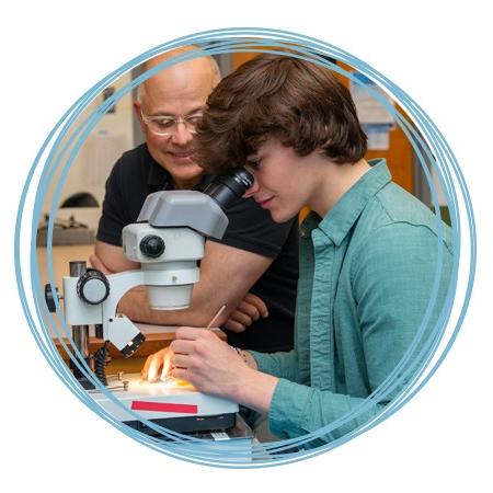 一位教师帮助学生观察显微镜