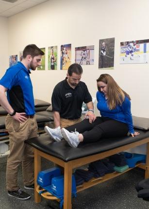 A professor and two students talking in the athletic training lab