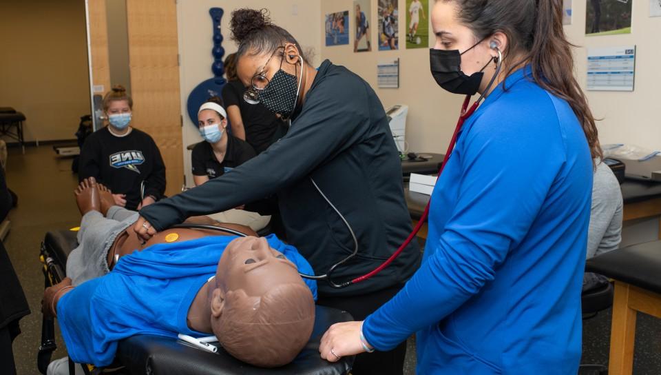 Athletic training students practice on a patient simulator