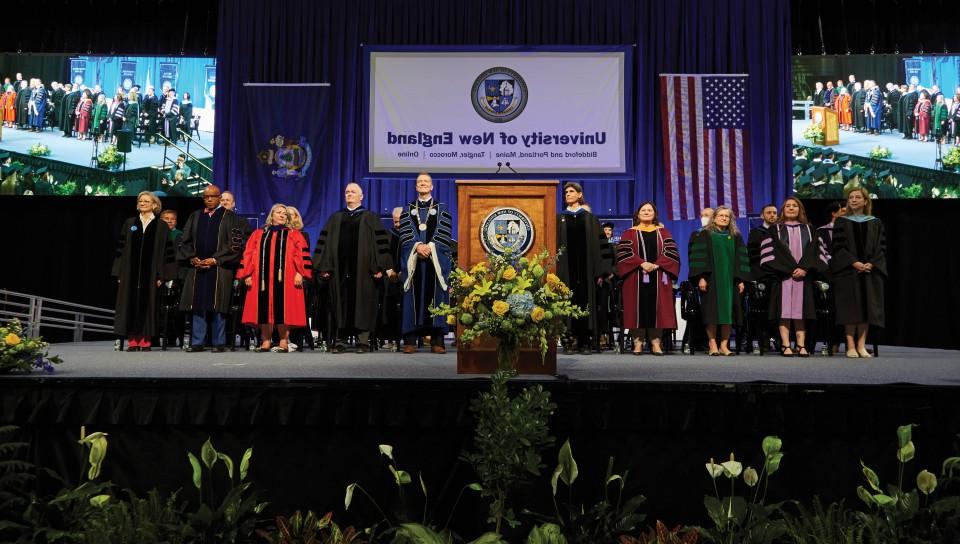 faculty stand on the stage at the U N E 2023 commencement ceremony