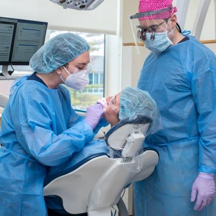 一名牙科学生和一名医师助理学生在牙科检查期间检查病人的口腔