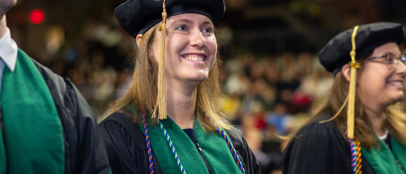 A student stands in the crowd in cap and gown at the 2023 U N E commencement ceremony