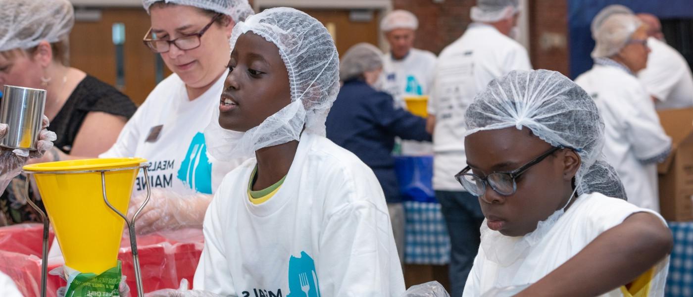 两名儿童志愿者帮助为缅因州的三餐打包食物