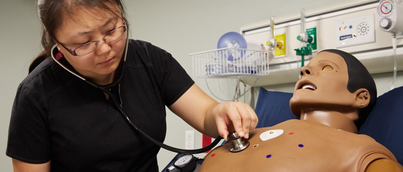 A physician assistant student uses a stethoscope to listen to the heartbeat of a patient