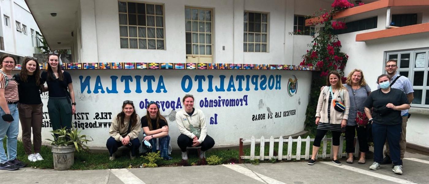 A group of students sit in front of a hospital building in Guatemala