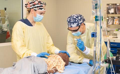 Two U N E D N P students practice on a patient simulator