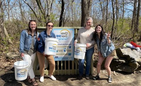 Students and a UNE staff member gather in front of the Clean Seas UNE beach cleanup kiosk at Freddy Beach