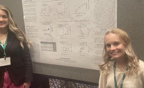 Lily Bennett, ’25 (left), and Hannah LaCourse, ‘23 (right) at the 2023 USASP meeting at Duke University in front of their poster.