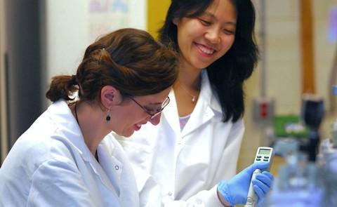 Ling Cao assists a student in a research lab