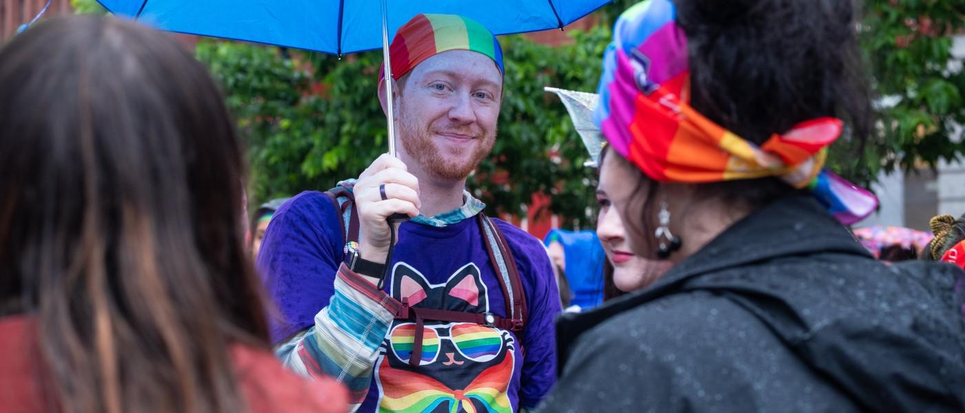 a UNE participant holds a colorful umbrella to fend off the rain